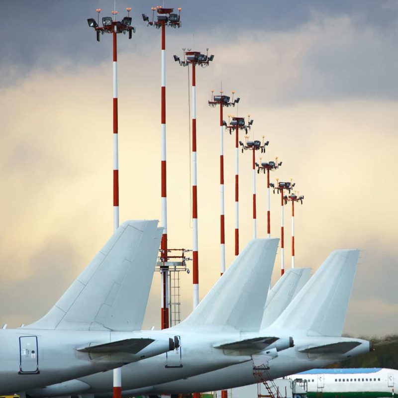 Aircraft tails parked at airport apron against a cloudy sky.